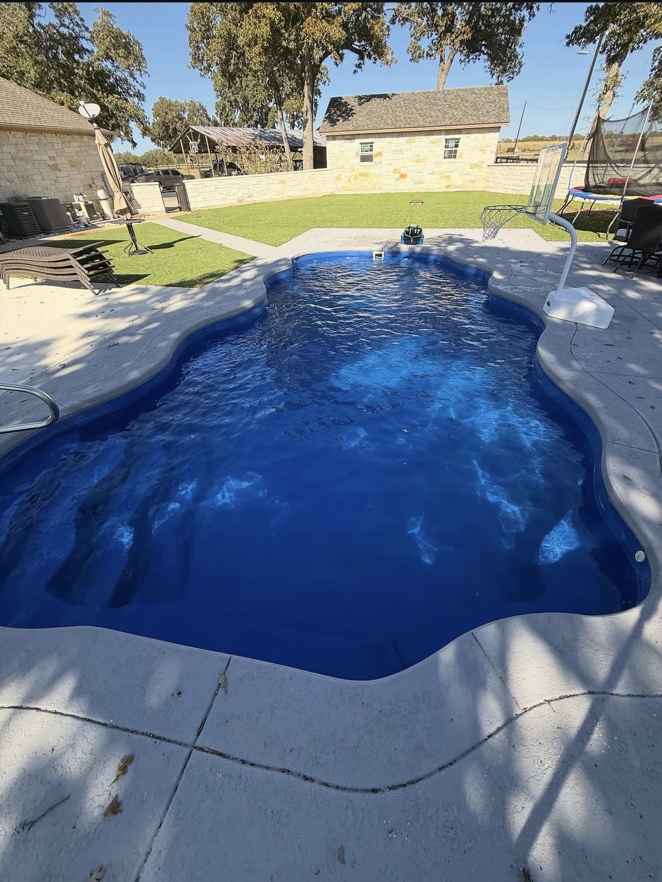 Deep blue resurfaced pool in a fenced backyard